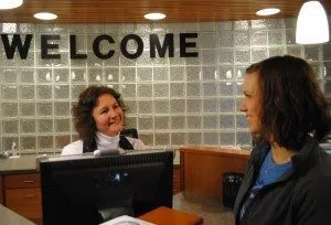 Student service worker greets student in front of welcome sign