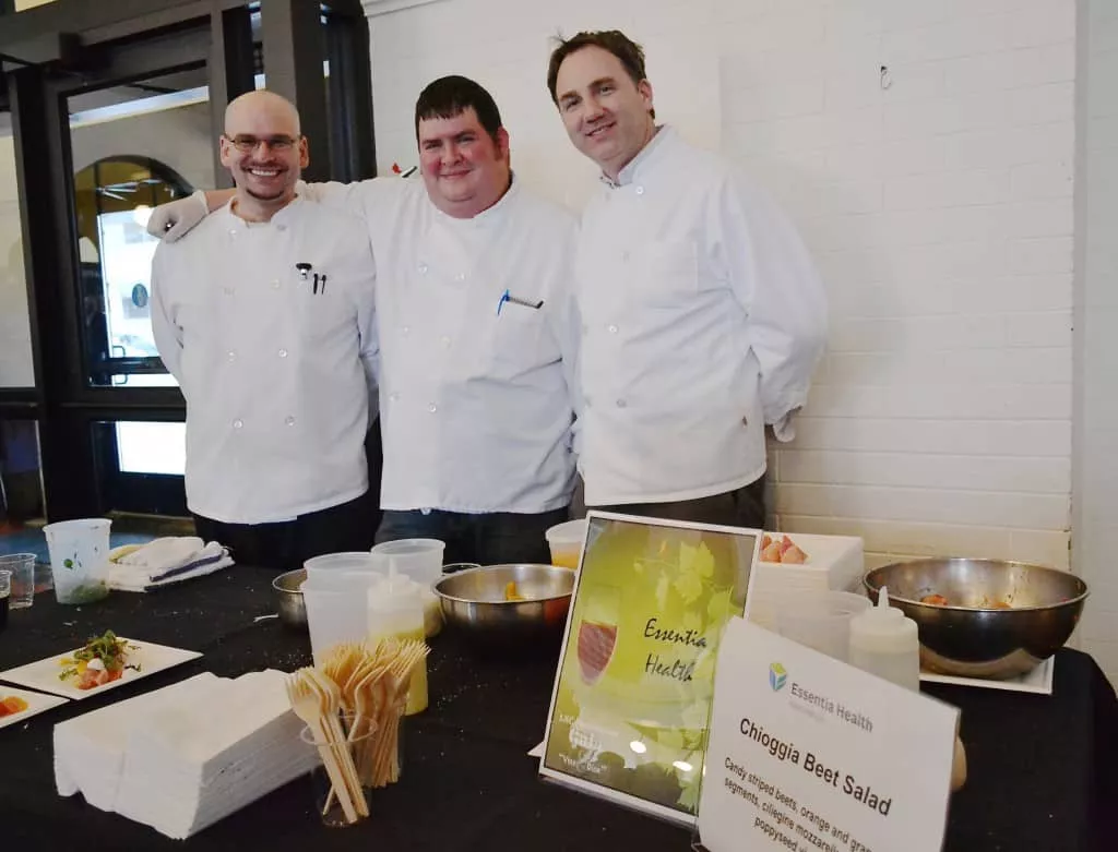Three food workers smiling and wearing white coats