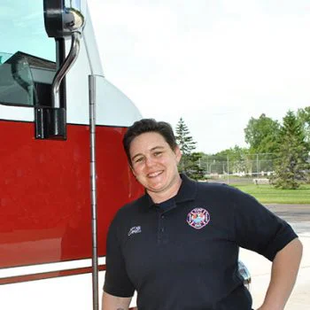Firefighting student stands in front of fire truck