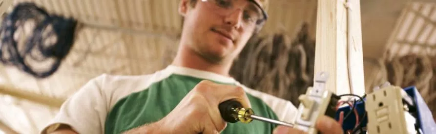 Business and industry student using a screwdriver on a light switch