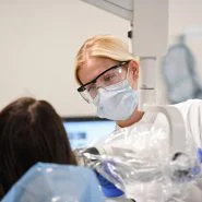 dental hygienist moves x-ray equipment close to patient's face