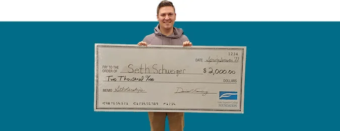 Photo of an LSC student holding a big scholarship check