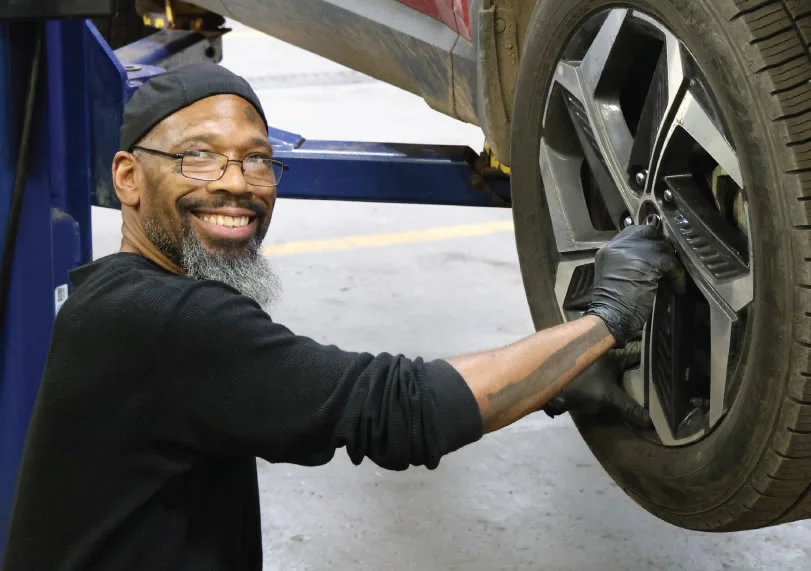 Photo of an automotive student working on a vehicle's wheel at Lake Superior College